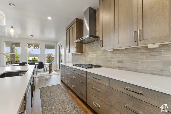 Contemporary kitchen featuring wood-finish cabinetry, white countertops, a tiled backsplash, and stainless steel appliances