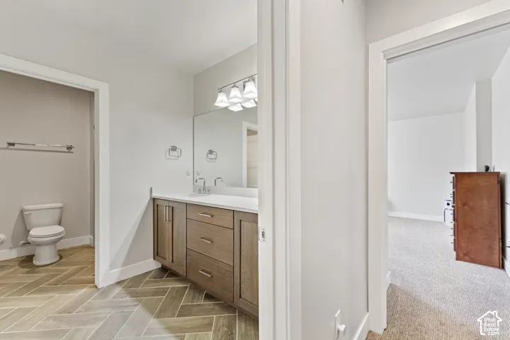Primary bathroom featuring a wood-finish vanity with dual drawers, white countertop, and chrome faucet
