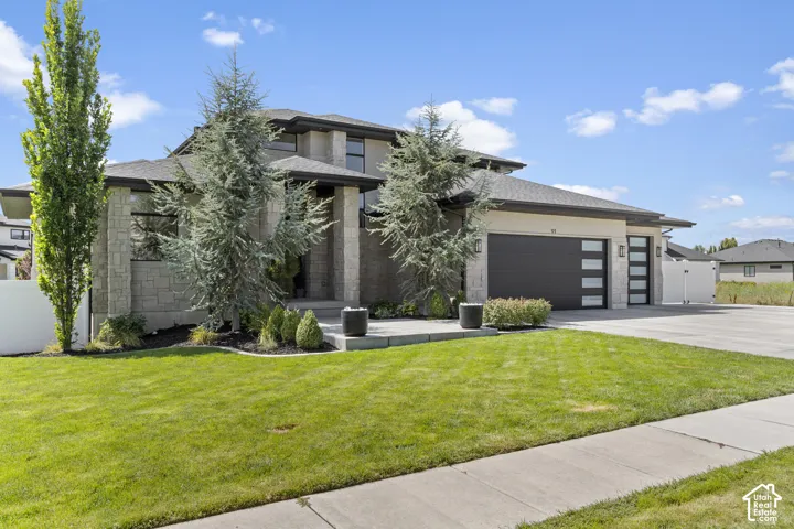 Modern two-story residence featuring a composite or stone exterior, multi-pane windows, and a contemporary flat-roofed design