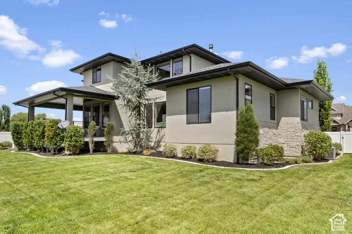 Contemporary home featuring a modern stucco and stone exterior with multi-level architectural detailing, expansive windows with dark framing, and a covered entry portico