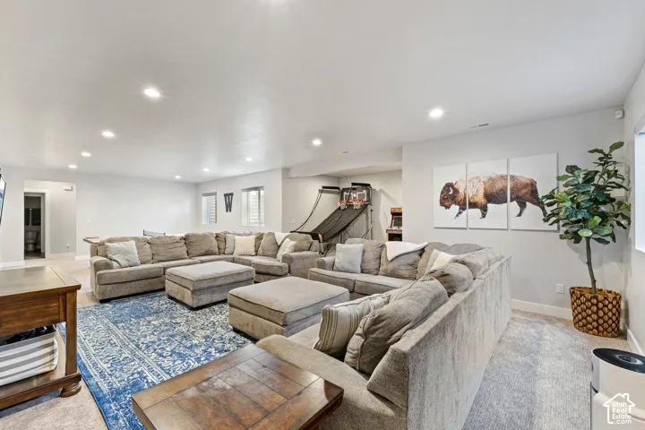 Recessed lighting illuminates an expansive room with light-toned walls and carpeted flooring