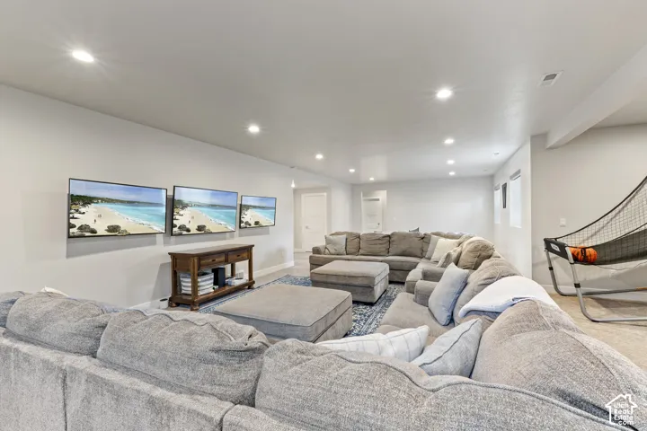Expansive recreation room featuring multiple wall-mounted flat-screen displays, recessed ceiling lighting, and generous seating areas with neutral upholstery