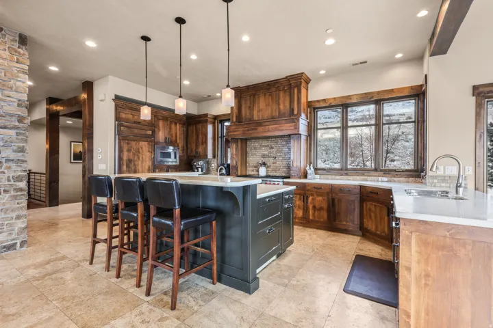 Gourmet kitchen featuring a large central island, recessed lighting, pendant lighting, wood-finish cabinetry, and stone tile flooring