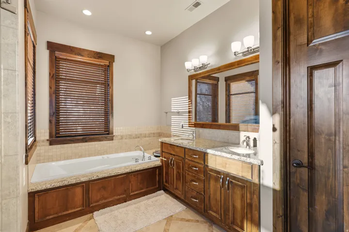 Primary bath main level. Built-in soaking tub with a stone surround, dual vanity with stone countertops, and recessed lighting