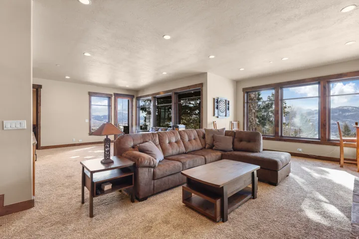 Expansive living area with recessed lighting, wall-to-wall carpeting, and wood-framed windows