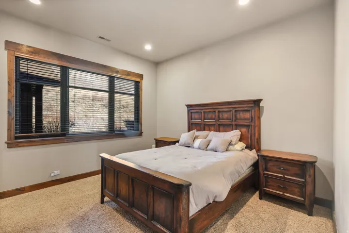 2nd bedroom with ensuite bath main level. Recessed ceiling lighting, wood-finish window trim, and carpeted flooring