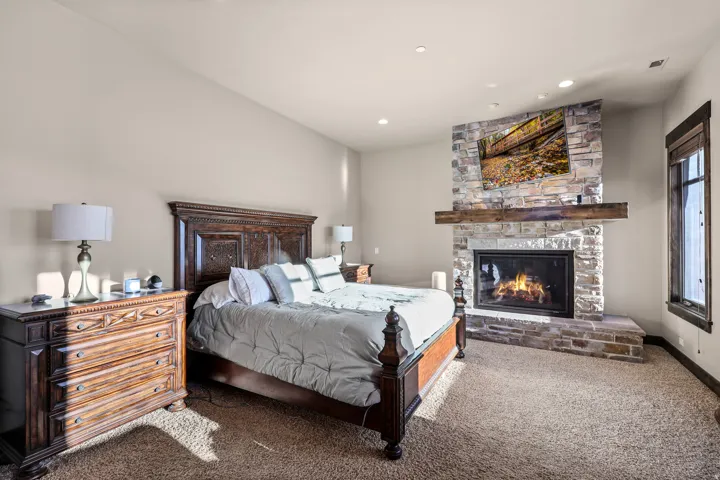 Stone-clad fireplace with a wood mantel. Primary bedroom main level.