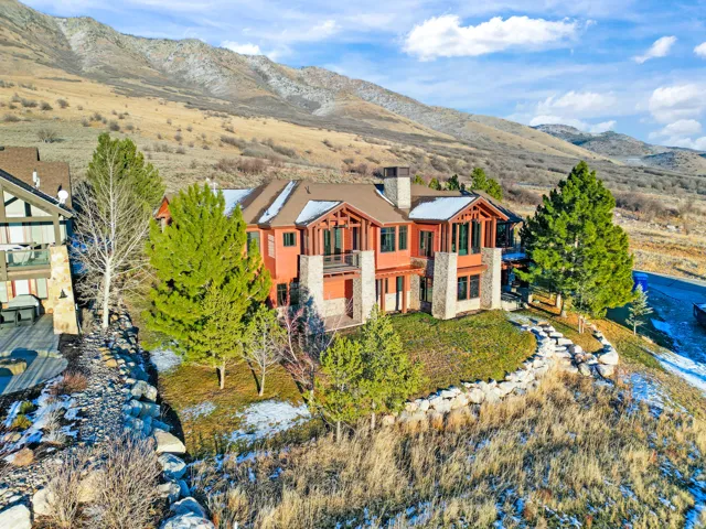 Terracotta-colored exterior with extensive stonework, multiple balconies, and a multi-level roofline, set against a mountain backdrop