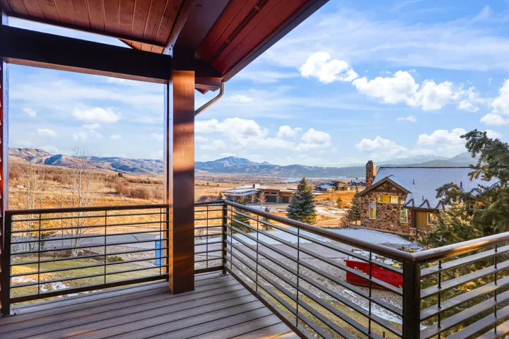 Expansive outdoor deck with wood-finish flooring, sturdy support beams, and horizontal metal railing