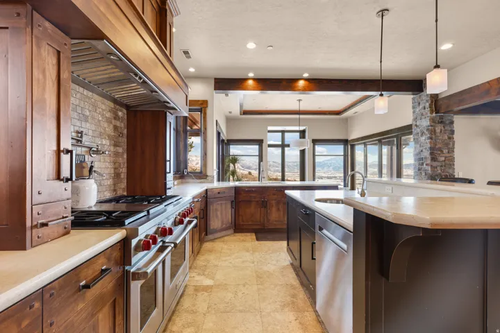 Gourmet kitchen with wood cabinetry, light-toned countertops, stone tile backsplash, and stainless steel appliances