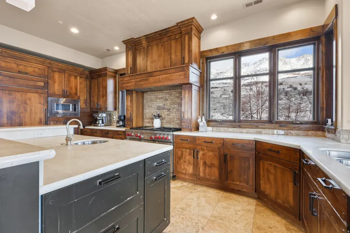 Kitchen featuring wood cabinetry, light-toned countertops, a built-in microwave, and a professional range with a custom hood