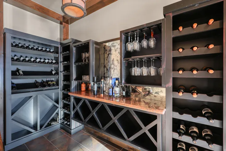 Custom built-in wine storage with X-cube shelving, integrated stemware racks, and a stone-finish countertop