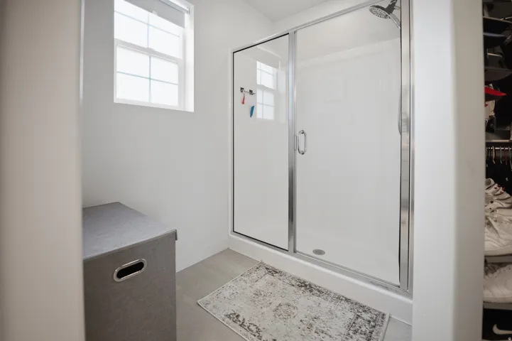 Shower with glass enclosure, chrome fixtures, and a window