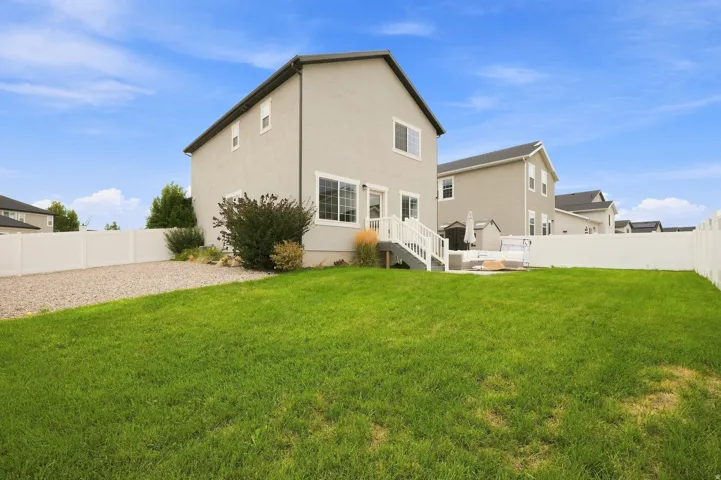 Expansive grassy yard with a gravel pathway and white privacy fencing