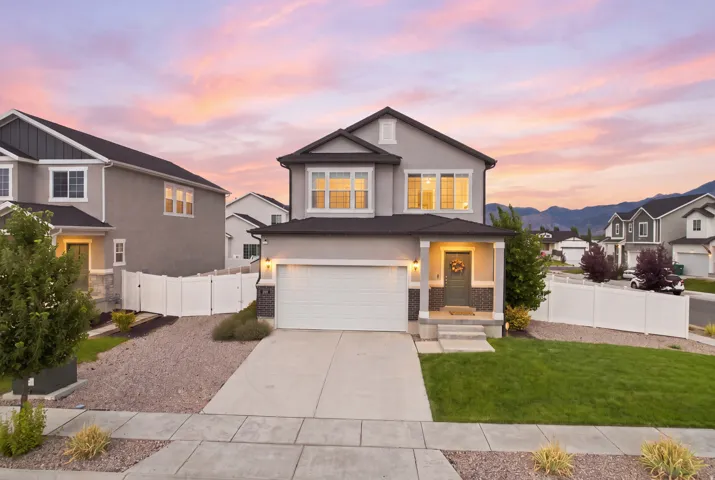 Contemporary stucco exterior with a covered entry, integrated garage, and a manicured lawn