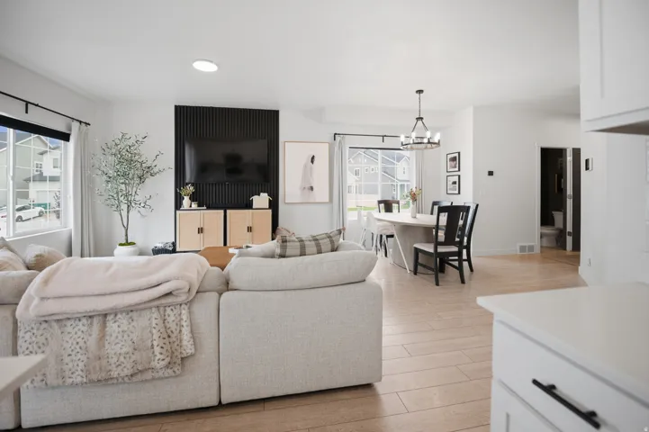Open concept living space featuring light wood-finish flooring, a contemporary dining chandelier, and recessed lighting