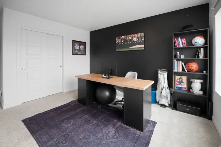 Recessed lighting with a dark accent wall, light-toned carpeting, and white trim