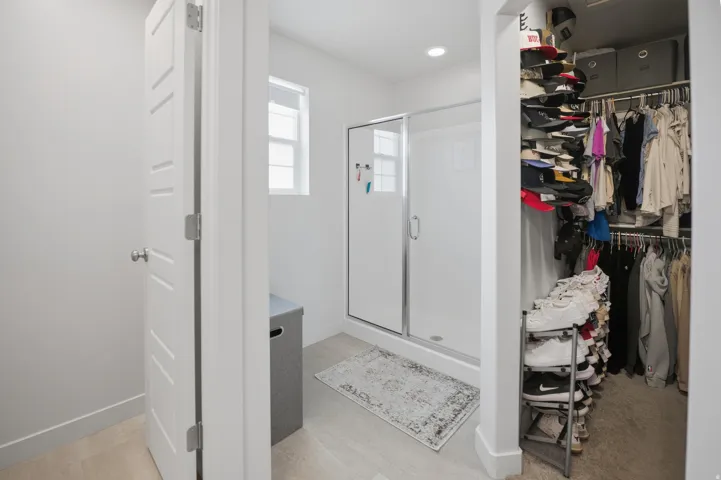 Shower enclosure with clear glass door, built-in shelving, and a small window