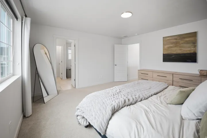 Bright interior with neutral carpeting, large window, and light wood-finish built-in storage
