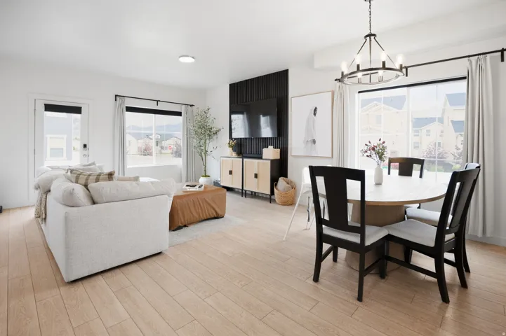 Open-concept living area with wood-finish flooring, a contemporary chandelier, and large windows