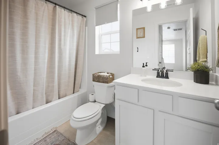 White vanity with an integrated sink, black hardware, and a framed mirror