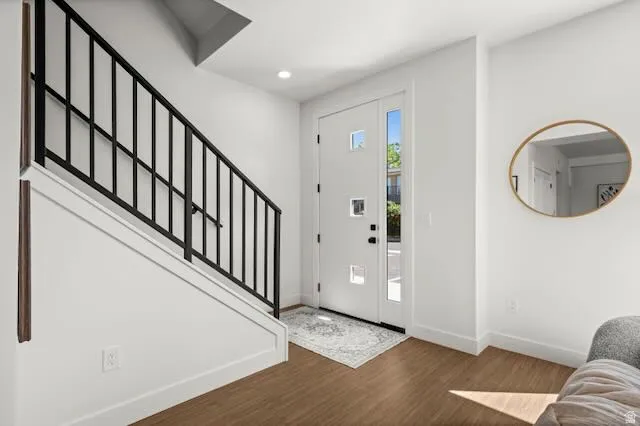 Contemporary entry door with multiple glass inserts, LVP flooring, and a modern staircase featuring black metal railings