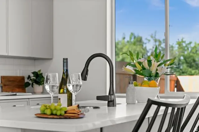 Kitchen island with a built-in sink, matte black faucet, light-toned countertops, and contemporary gray cabinetry