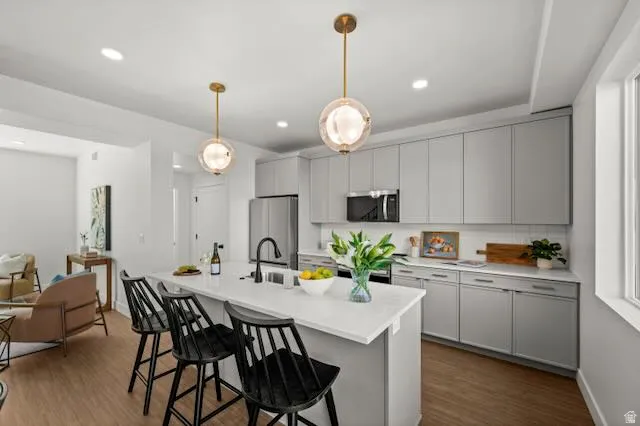 Kitchen with light gray cabinetry, stainless steel appliances, a white island, and LVP flooring