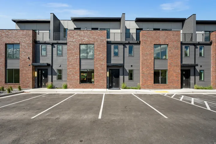 Modern townhome exteriors featuring red brick accents, dark gray siding, and top floor balconies