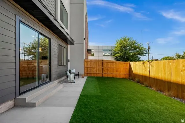 Private backyard featuring a full wood fence, artificial turf, and a concrete patio