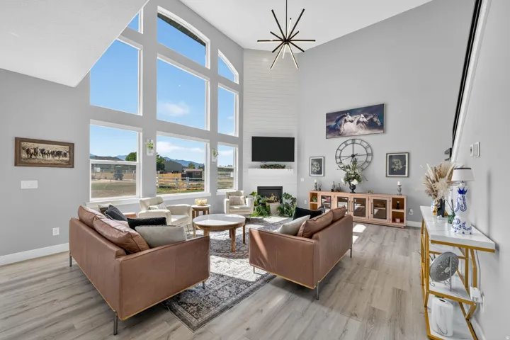 Open-concept living area featuring high ceilings, wood-finish flooring, a contemporary staircase and large windows