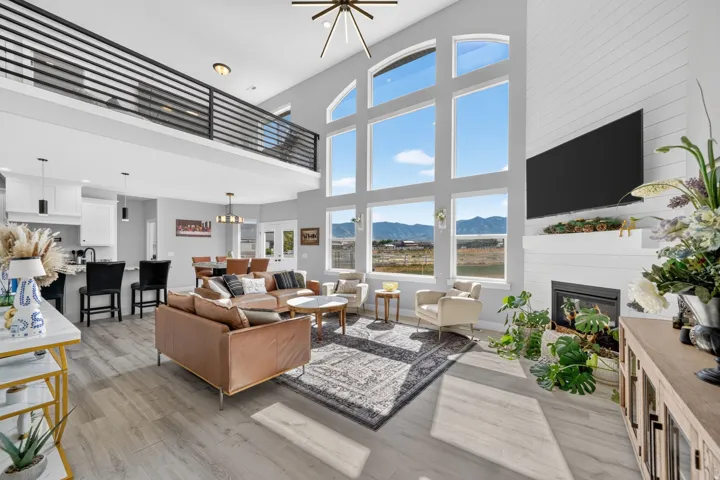 Open-concept living area featuring high ceilings, wood-finish flooring, a contemporary staircase and large windows