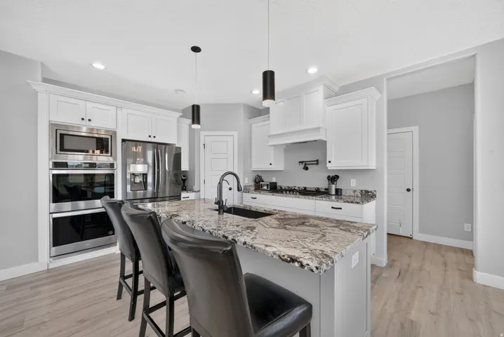 Modern kitchen featuring white cabinetry, light-toned wood-finish flooring, and a large island with a patterned countertop