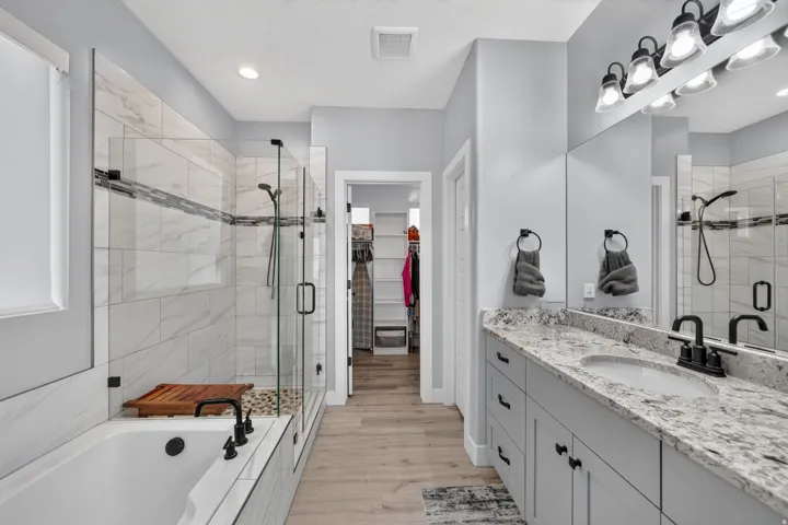 Primary bathroom with dual vanity, soaker tub, and euroglass shower.