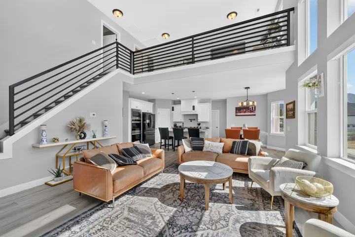 Open-concept living area featuring high ceilings, wood-finish flooring, a contemporary staircase and large windows