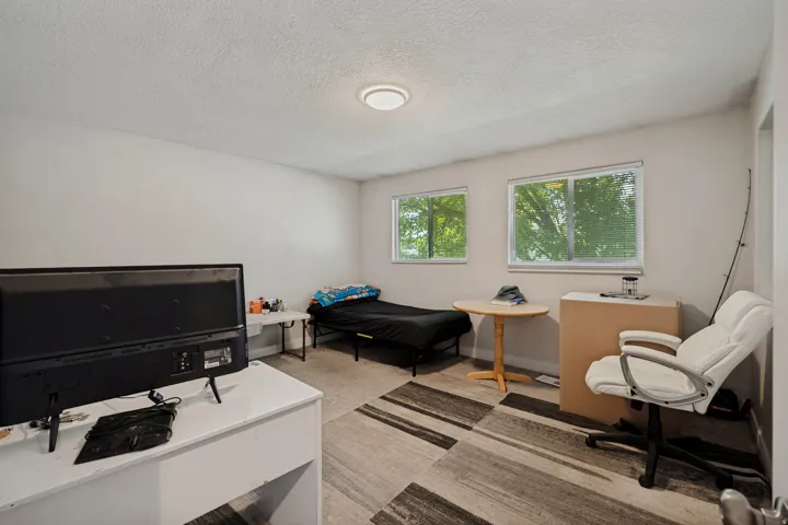 Recessed lighting with a round fixture, two windows, textured ceiling, and striped pattern carpet flooring