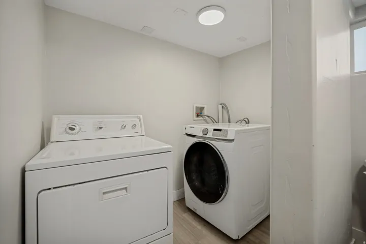 Laundry area with light wood-finish flooring and a flush-mount ceiling light fixture