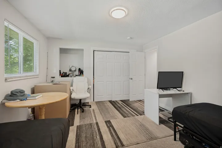 Integrated closet with bi-fold doors, recessed alcove, window with blinds, and flush-mount ceiling light