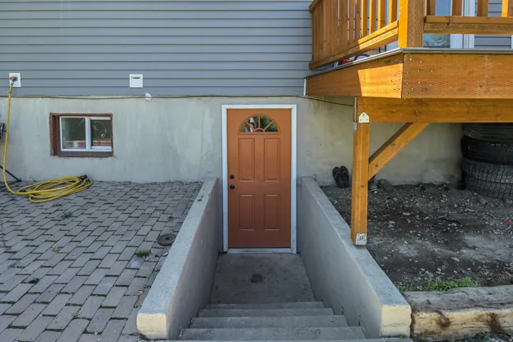 Exterior entry with a wood-finish door, concrete stairs, and a paved patio area