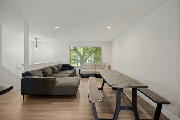 Recessed lighting, wood-finish flooring, white walls, large window, pendant light fixture