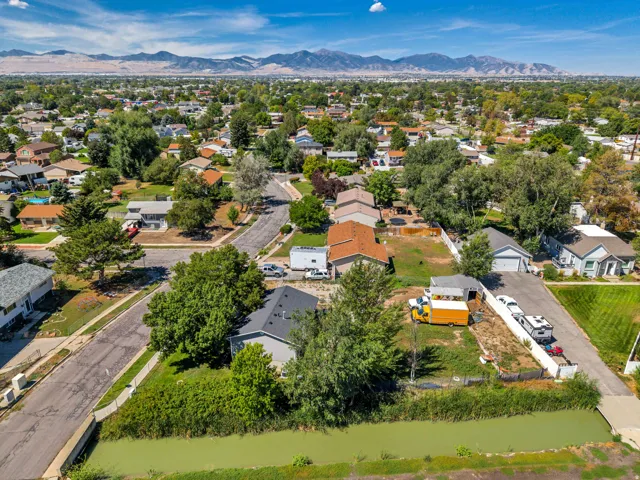 Residential neighborhood featuring varied housing styles, mature trees, and mountainous terrain in the background