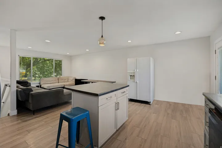Open-concept living area with wood-finish flooring, recessed lighting, and a kitchen island with storage