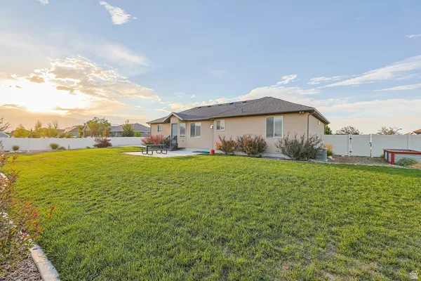 Expansive grassy yard with a white privacy fence