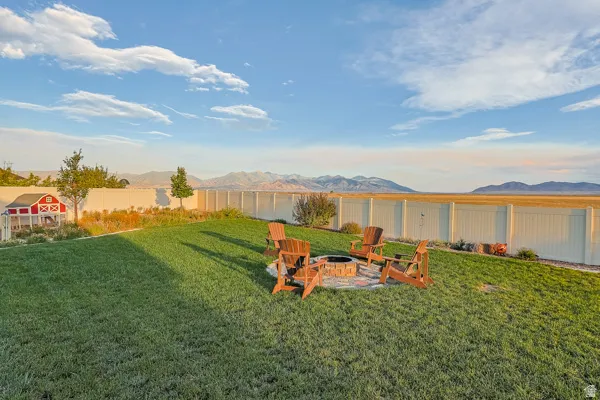 Expansive backyard featuring a manicured lawn, established fire pit area, and a privacy fence