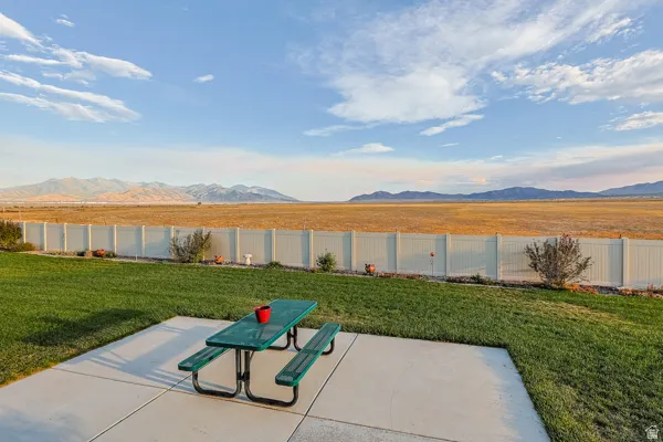 Expansive lawn area with a concrete patio, bordered by a white privacy fence