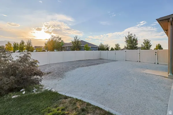 Expansive gravel area with white privacy fencing, multiple access gates, and a concrete patio section