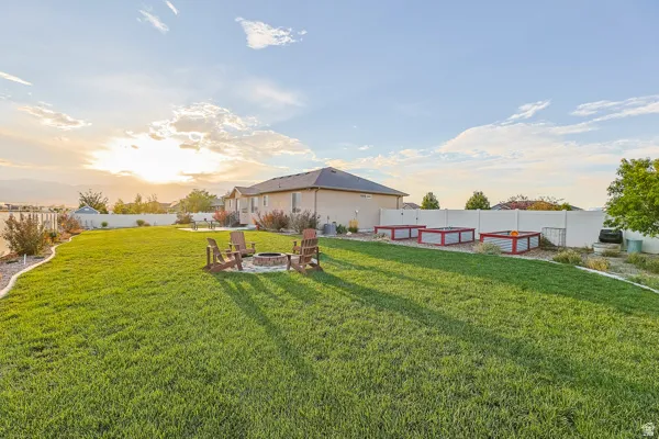 Expansive lawn area with a built-in fire pit, surrounded by a white privacy fence
