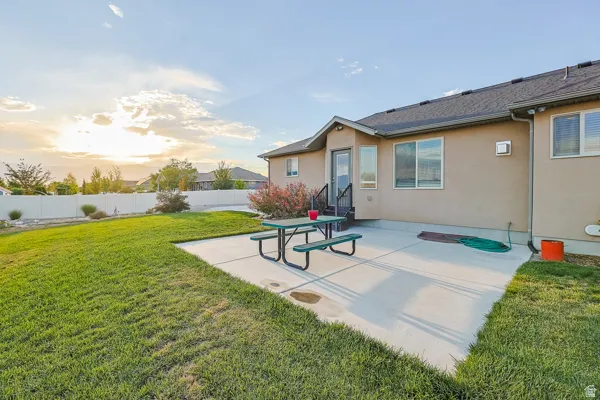 Expansive concrete patio with direct outdoor access, bordered by a manicured lawn and a white privacy fence