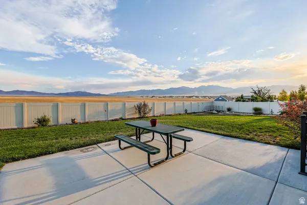Expansive backyard featuring a concrete patio, grassy area, and white privacy fencing