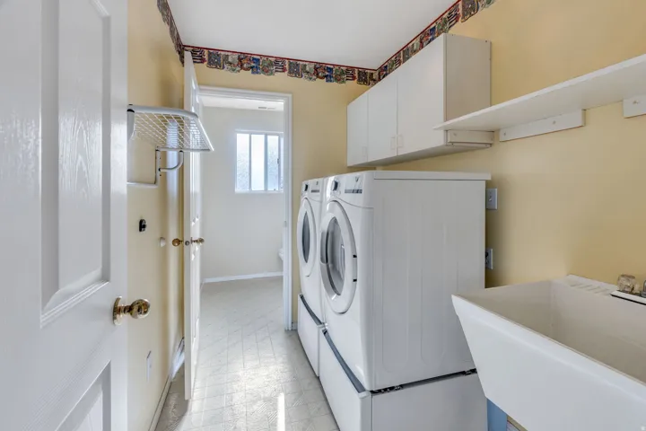 Laundry room featuring a utility sink, wall-mounted cabinetry, and a storage shelf